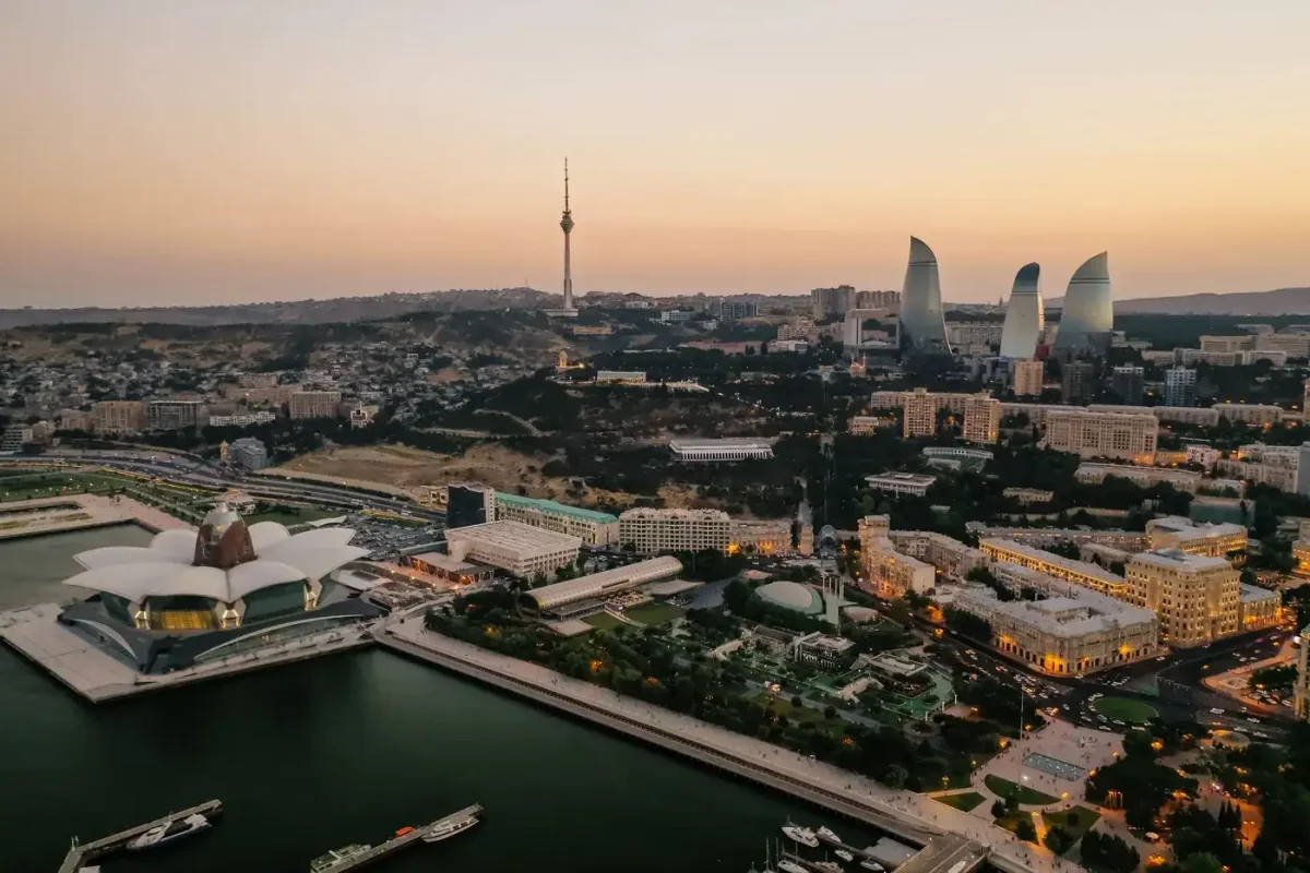 Best eSIM for Azerbaijan: aerial view of the Baku skyline and Flame Towers over the Caspian Sea at dusk.