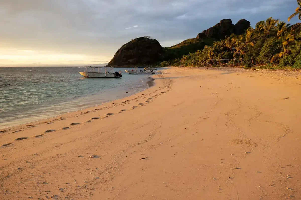 Best eSIM for Fiji: sunset over a Yasawa Islands beach with boats moored offshore
